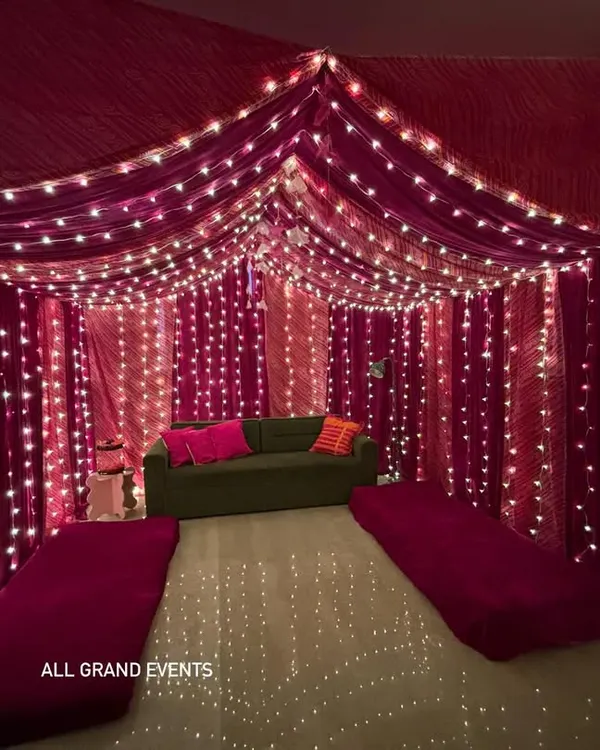 I transformed this living room into a beautiful tent-like space using vibrant pink bandhani and leheriya fabrics. The ceiling and walls are draped and lit with fairy lights for a magical, festive feel.