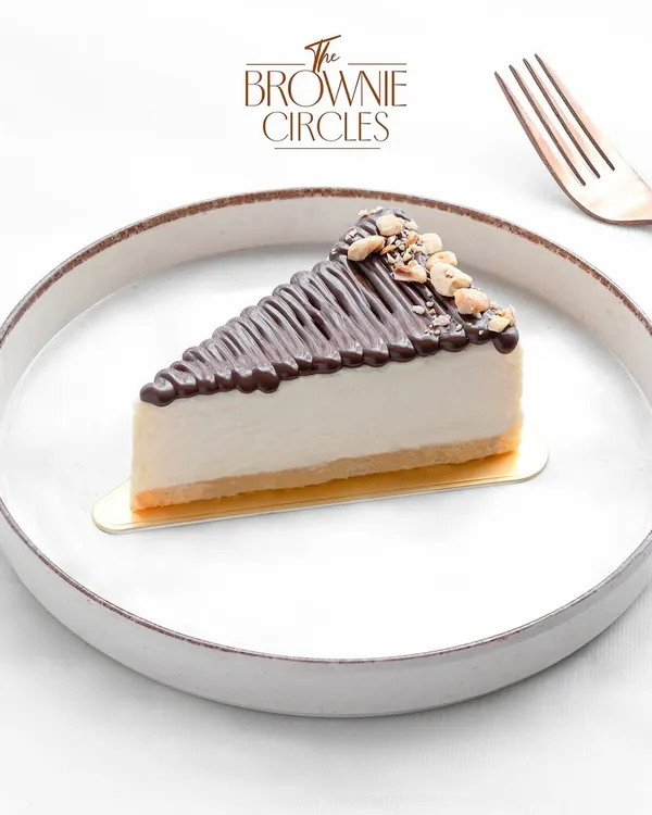Our baked Hazelnut Cheesecake is a nutty delight. A creamy cheesecake base is infused with hazelnut flavor, topped with a chocolate drizzle and crunchy roasted hazelnuts.