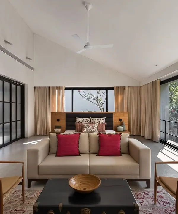 This spacious master bedroom in the Mango Orchard House features high, pitched ceilings and wall-to-wall glass doors that open to a private balcony. The room is large enough to accommodate a comfortable seating area, creating a versatile private retreat.
