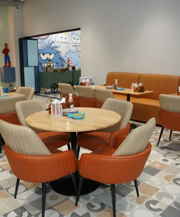 A view of our spacious and modern cafe, with comfortable booth seating and round tables. It's the perfect spot for parents to relax.