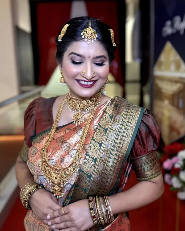 A radiant South Indian bride with a classic makeup look. We used warm gold tones on the eyes and a deep maroon lip to complement her silk saree and temple jewelry.