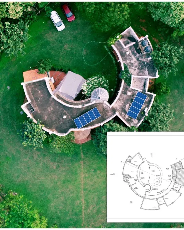 This image shows the aerial top-down view of the C-shaped farmhouse alongside its architectural floor plan. This helps visualize how the unique curved design translates from a 2D drawing to a three-dimensional structure.