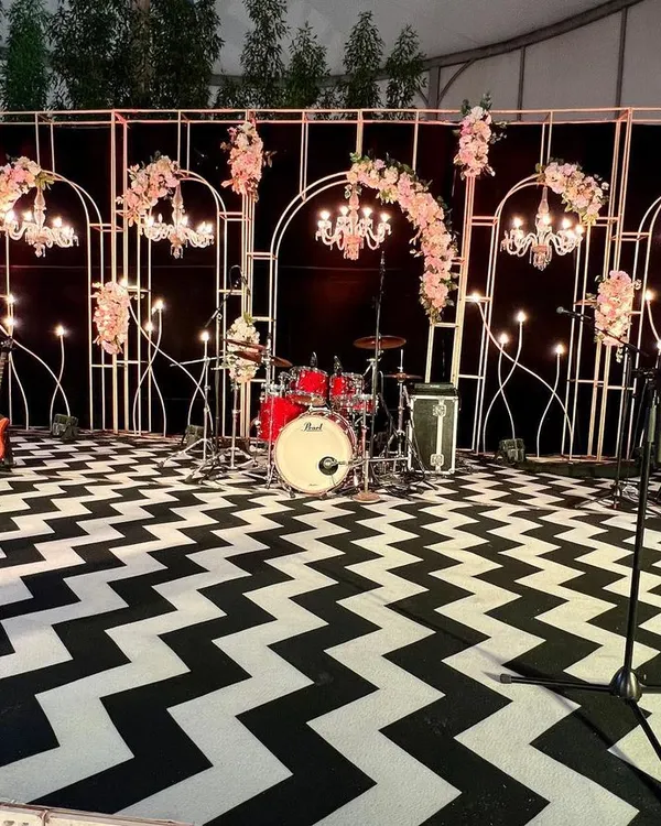 The complete stage setup for the 60th birthday bash. The design featured a striking chevron-patterned floor, elegant floral arrangements, and a full backline for the live band.