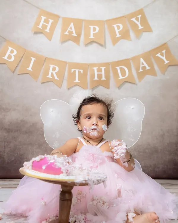 A little fairy in a pink dress having the best time during her cake smash session. The frosting on her face says it all!