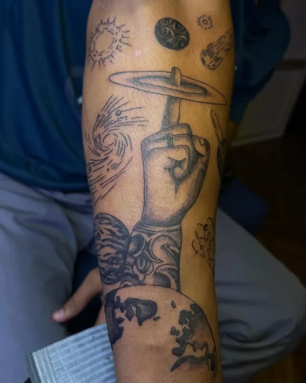 This custom arm sleeve combines various cosmic elements, including planets, a swirling galaxy, and shooting stars. Each element was chosen by the client to build a personal narrative.