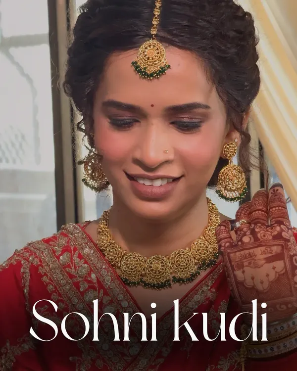 A beautiful 'Sohni Kudi' on her wedding day. This Punjabi bridal look features soft, smoky eyes and a radiant glow that perfectly complements her red attire and golden jewelry.