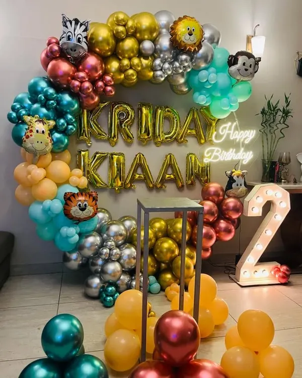 A vibrant jungle safari theme for a 2nd birthday. This circular balloon arch is filled with colorful chrome balloons and various animal head foils like a tiger, giraffe, and zebra.