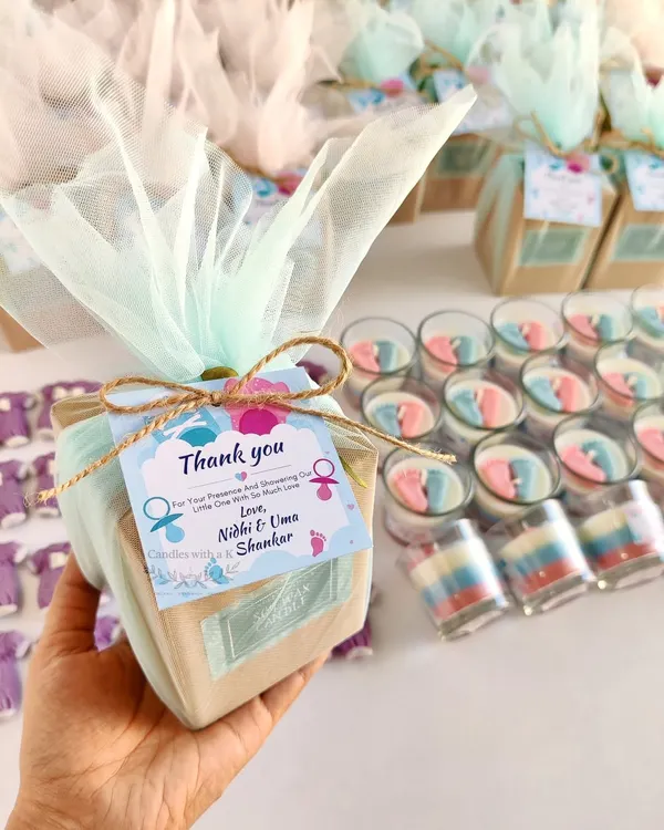 A beautiful baby shower return gift box I created for Nidhi and her family. It features a layered votive candle with tiny pink and blue baby feet and a purple baby onesie wax sachet, all perfectly packed and ready to delight guests.