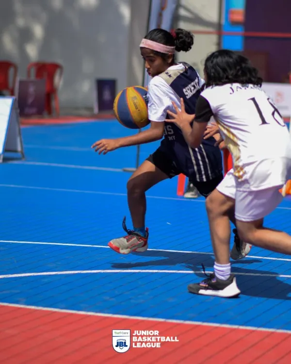A young athlete drives past her defender in a display of skill and determination. I create an environment where girls can compete fiercely and develop their basketball abilities in the Junior Basketball League.