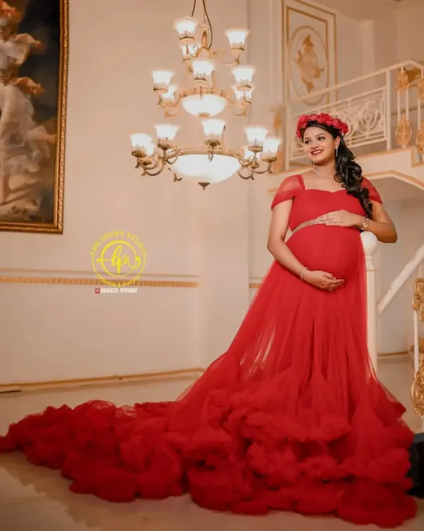 Feel like a queen in this stunning red ruffled trail gown, a perfect choice for a glamorous indoor maternity shoot. The floral headpiece adds a soft, romantic touch.