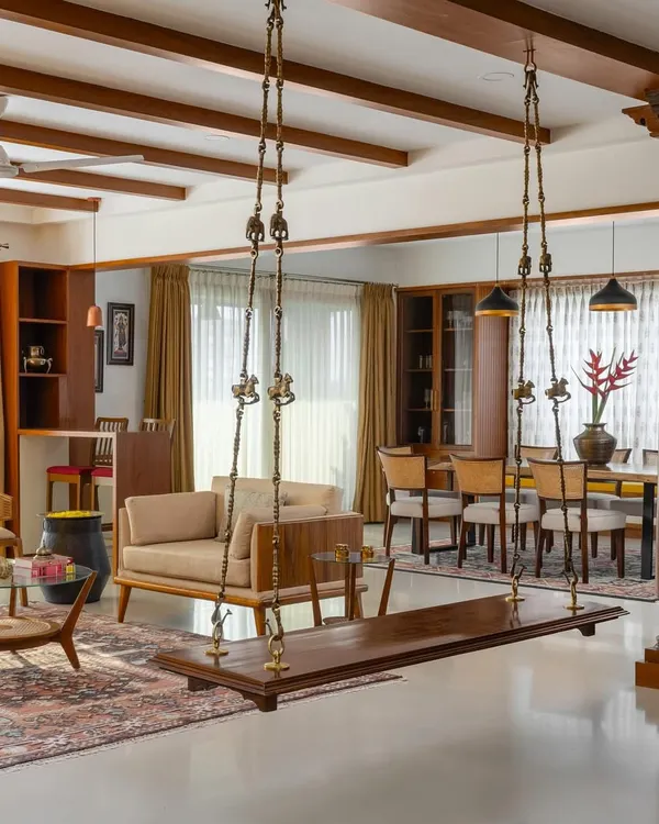 This living room from our 'Vasudhalayah' project embodies our love for South Indian charm fused with contemporary living. The antique Chettinad pillars and traditional wooden swing create a warm, ethnic welcome, balanced by modern furniture and an earthy color palette.