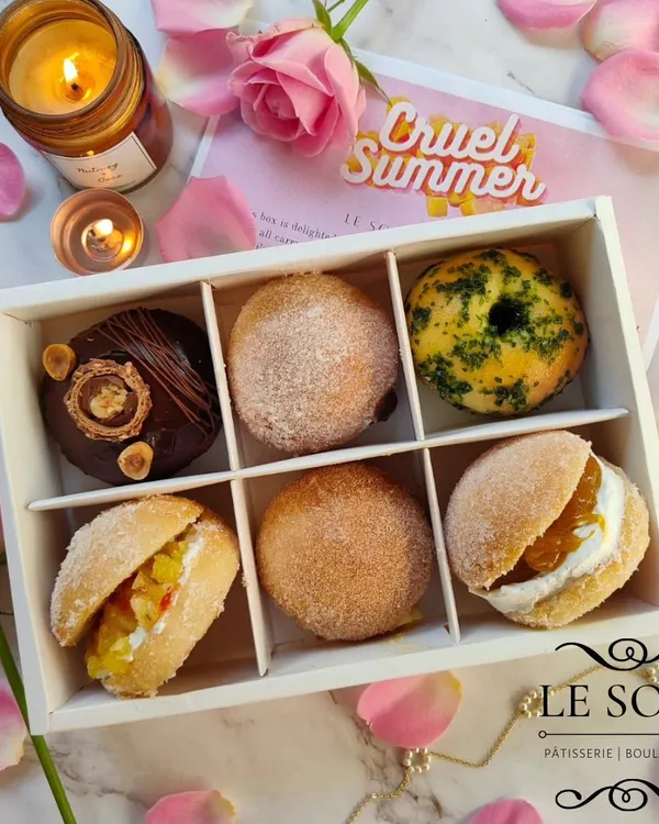 Here's an assortment box from my 'Cruel Summer' Valentine's menu. It shows the variety I offer, from filled doughnuts to doughnut sandwiches, with both sweet and savory options.