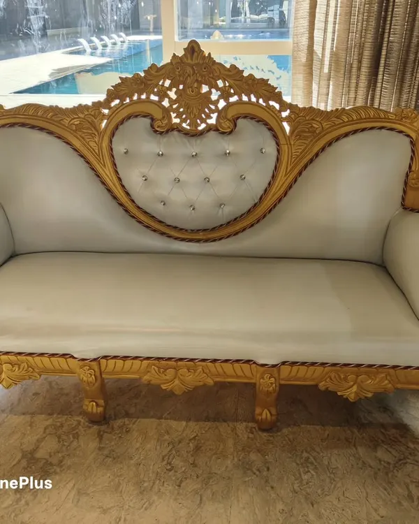 A close-up of our beautiful golden and white wedding sofa. This piece is a favorite for stage setups and adds a touch of royalty to any event. It is available for rent.