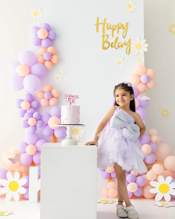 Turning five is a big deal. This portrait captures the birthday girl standing proudly next to her cake in a beautiful pastel flower-themed setup we designed together.