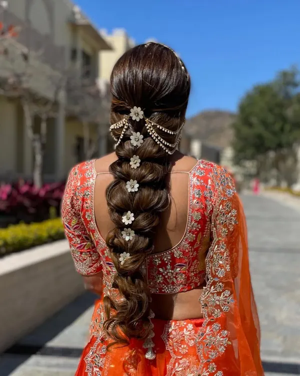 A close-up of a stunningly detailed bridal braid. I used floral accessories and a pearl hair chain to create a look that is both traditional and incredibly photogenic, perfect for a daytime wedding.