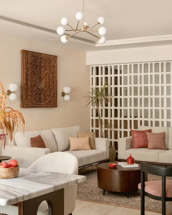 This living room is where modern comfort meets timeless Indian artistry. I anchored the space with a large, hand-carved wooden panel and a delicate jali screen, creating a backdrop that feels both grand and personal. The neutral sofas and contemporary lighting ensure the room remains bright and welcoming, a perfect space for family stories to unfold.
