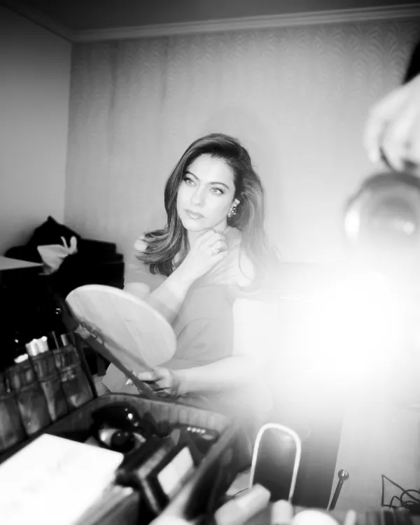 A behind the scenes black and white photo of Kajol getting ready for the 'Do Patti' trailer launch, looking stunning in a custom red gown.