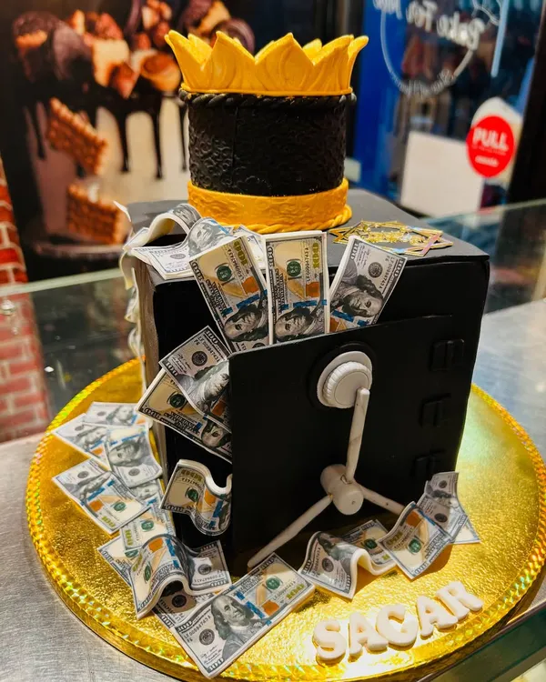 Celebrate a big win with this incredible money vault cake. The edible vault is overflowing with meticulously crafted fondant dollar bills, topped with a golden crown.
