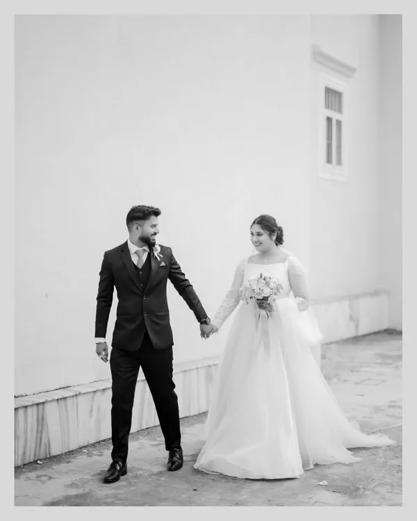 A classic black and white photograph of the bride and groom walking hand-in-hand after their church ceremony. This timeless style emphasizes emotion and connection.