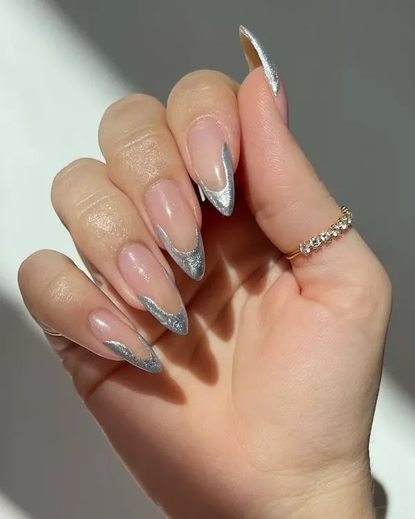 A sleek and futuristic take on the French manicure, featuring sharp, stiletto nails with a sparkling silver glitter chrome tip. This design is perfect for making a bold and glamorous statement.