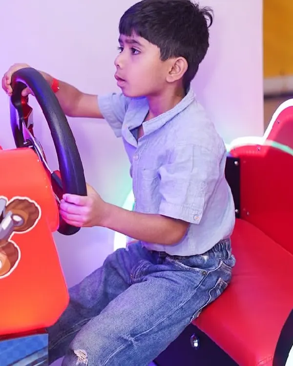 A young boy gets into the driver's seat of our "Happy Racing" arcade game, ready for a virtual race.