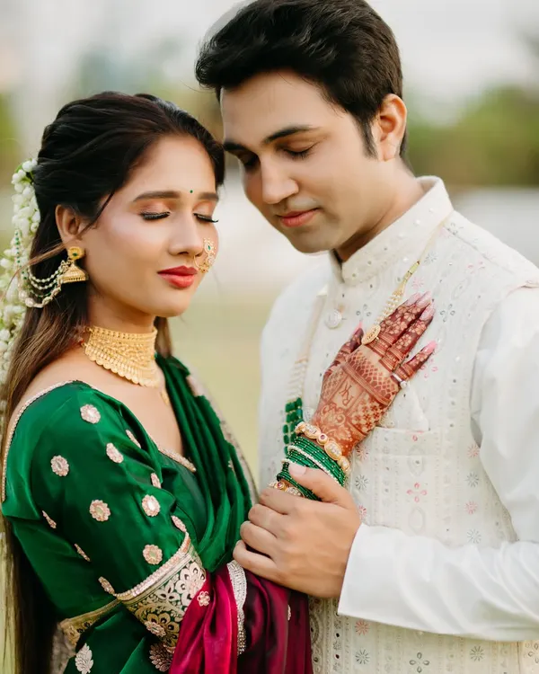 A serene and intimate portrait focusing on the bride's intricate mehendi and the groom's gentle touch. Dressed in traditional Maharashtrian attire, their closed eyes and soft smiles convey a deep sense of peace and love.