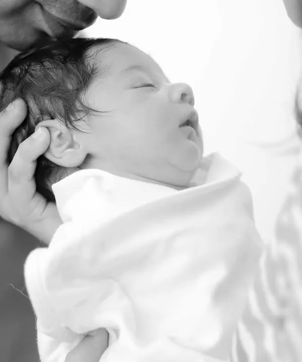 A tender black and white moment of a newborn being held by their parents. This style emphasizes emotion and connection.