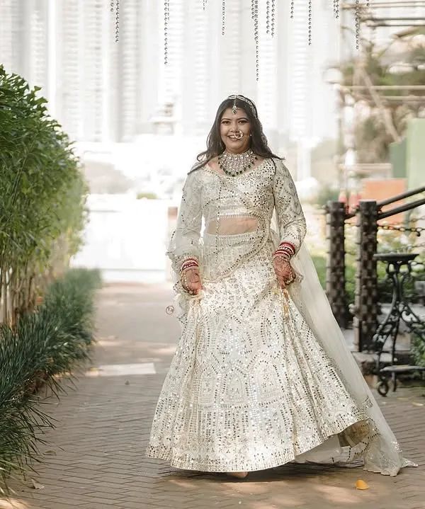 This is what it's all about. Seeing our bride, radiant and happy, walking in a lehenga that was once just a dream. This handcrafted ivory lehenga, shimmering with intricate mirror work, was designed to make her feel like the main character of her story.