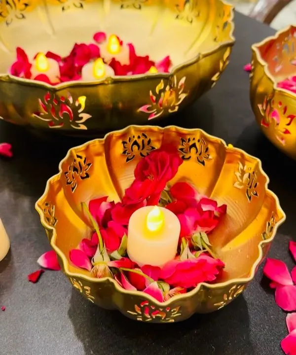 A close-up of our lotus-cutwork urli bowls, handcrafted from metal with a gold finish. Filled with water, rose petals, and floating candles, they create a serene and beautiful centerpiece for Diwali and other festivities.
