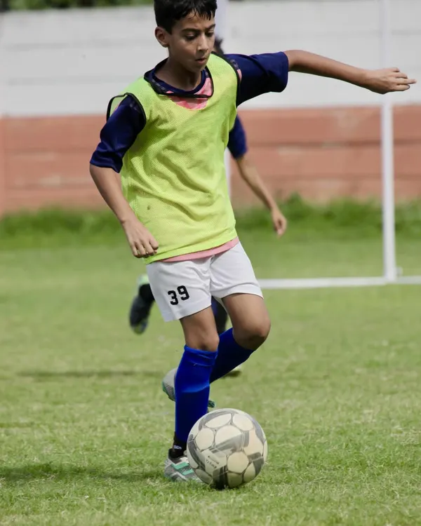 A young player focuses on his dribbling technique, maneuvering the ball with precision. This fundamental skill is the building block for every great player.