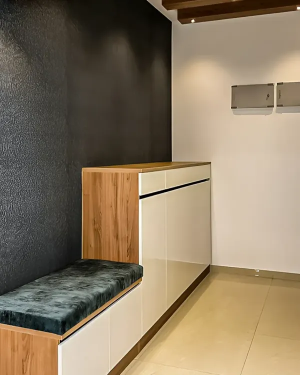 A sleek and modern entryway unit featuring a combination of wood and white gloss finishes. The design includes a comfortable cushioned bench for sitting and concealed shoe storage below.