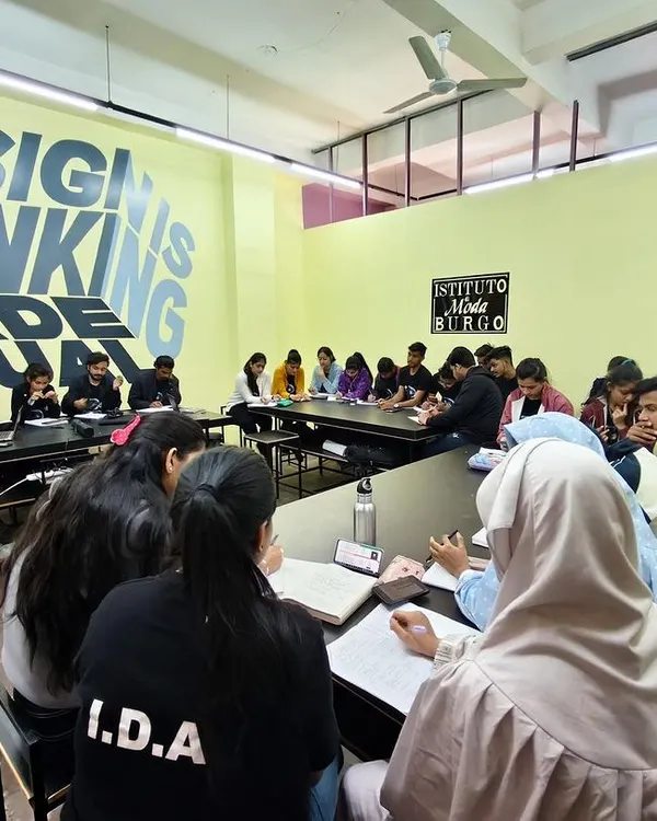 A full view of a workshop in session, with the "Design is Thinking Made Visual" motto on the wall. This captures the energy of our collaborative learning environment at Istituto Moda di Burgo.