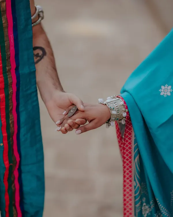 A close-up on the hands, symbolizing the divine and eternal connection of Radha and Krishna. The traditional attire and jewelry add to the authenticity of this themed pre-wedding shoot.