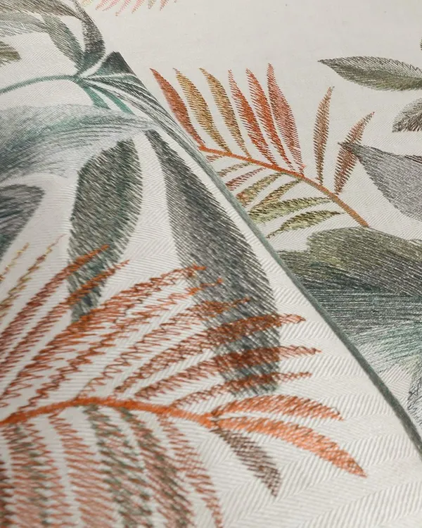 This close-up showcases the artistry of our 'Jardin Ephémère' collection. An artist's hand-drawn sketch is reinterpreted on embroidered linen, with varied stitches reflecting the spontaneous character of a pencil drawing and adding depth to the foliage.