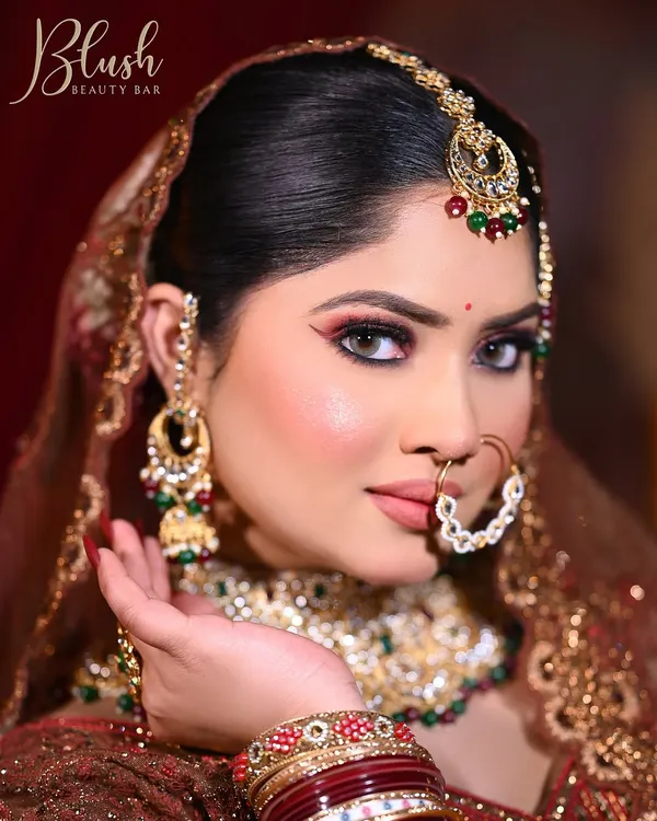 A close-up of a classic Indian bridal look. I've used a winged eyeliner and red tones on the lower lash line to define the eyes, complemented by a flawless base and heavy traditional jewelry for a complete wedding day look.