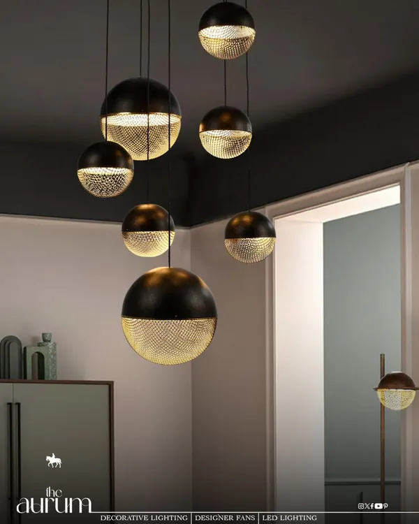 This cluster of spherical pendants features a unique dual-finish of solid black and perforated gold. The design casts a beautiful, patterned light, demonstrating where lighting becomes a form of architecture itself.