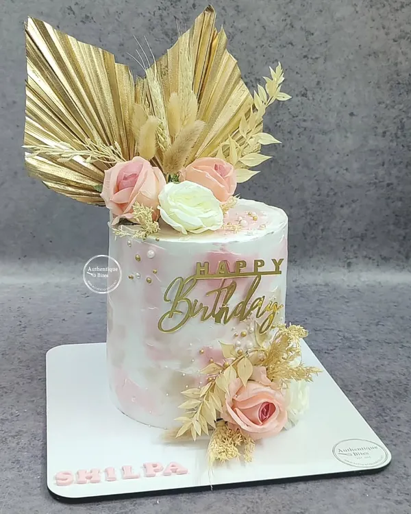 A beautiful rustic floral cake. This design combines a pink marble effect with dried palm leaves, wheat stalks, and delicate pink and white roses for a chic, boho look.