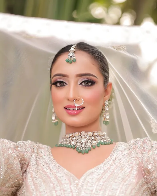 A breathtaking close-up of our modern bride. I created a sharp, defined eye with a subtle shimmer and a soft pink lip to complement her white lehenga and emerald jewelry.