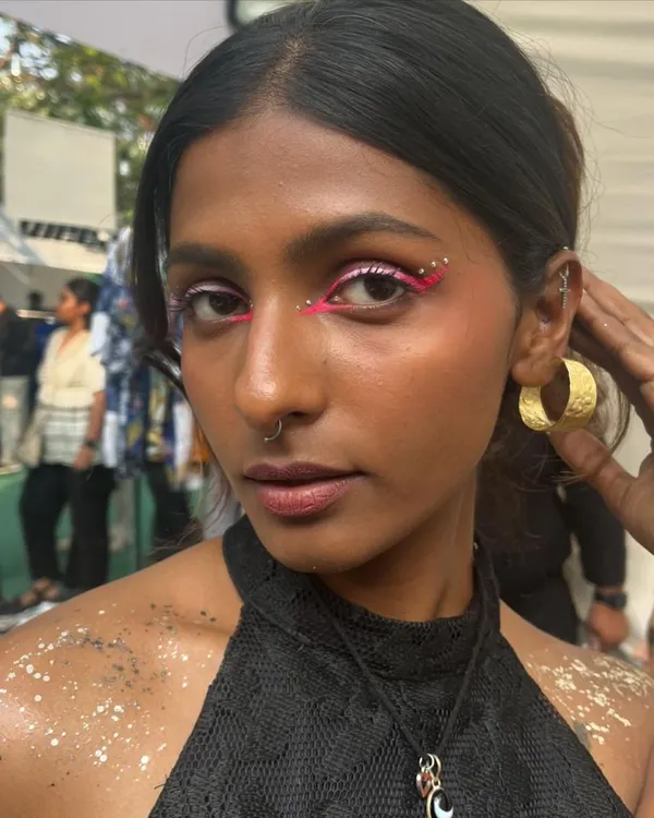 A fun and creative look from the Under25 Summit. This features a bold pink graphic liner with rhinestones and body glitter.