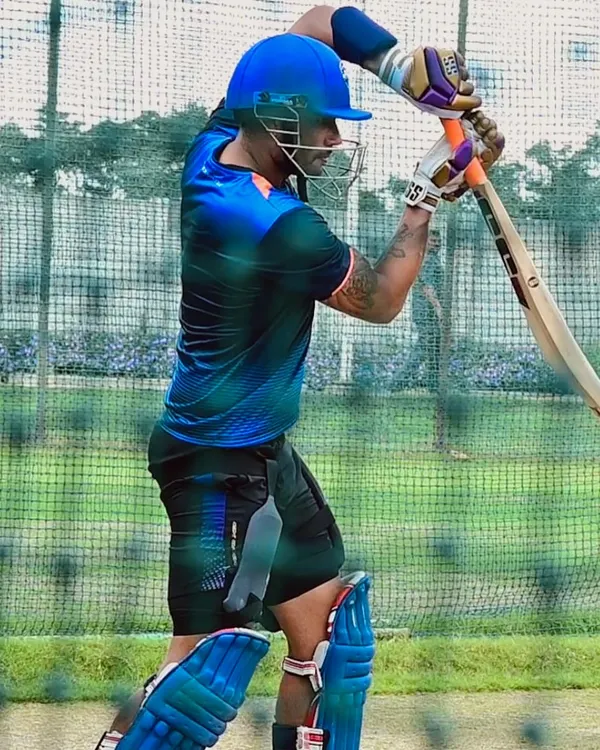 A batsman in full gear, practicing his stance in the nets. The focus is on balance, head position, and being ready to execute a powerful shot.