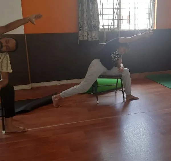 In this chair yoga session, students practice a supported variation of Virabhadrasana (Warrior Pose). Using a chair helps maintain alignment and stability, making powerful poses accessible to people with knee issues or balance concerns.