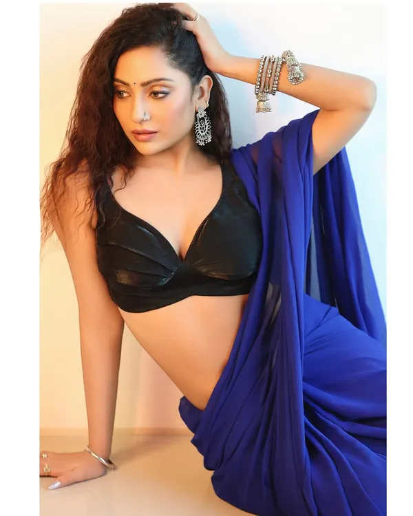 A modern interpretation of a saree look, pairing a vibrant blue saree with a stylish black bralette. The pose is relaxed yet elegant, perfect for a contemporary fashion portfolio.