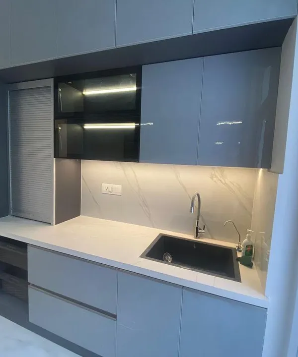 This sleek, grey modular kitchen features handleless cabinets and built-in appliances for a clean, minimalist look. The under-cabinet lighting provides excellent task lighting.