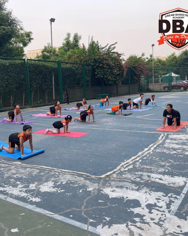 A wide view of our outdoor yoga class on the basketball court. We believe in using our primary training space to integrate new skills, making yoga a natural part of our athletes' routine.