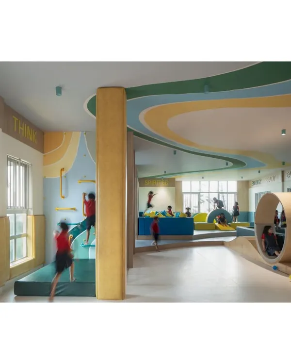 Another view of the soft-gym, a space designed for active bodies and curious minds. The undulating landscape, climbing wall, and rolling wheel provide endless opportunities for physical challenges and imaginative play.