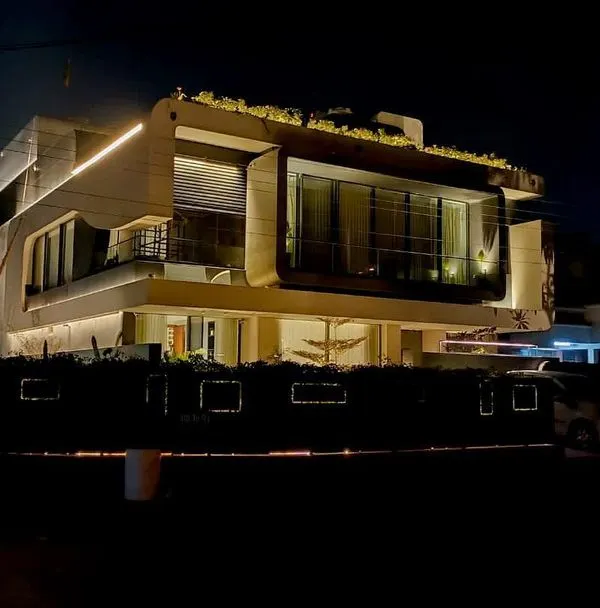 This full view of a modern residence in Panchkula demonstrates how linear lighting can trace the home's unique geometry. The rooftop greenery is also subtly illuminated, integrating the structure with its landscape.