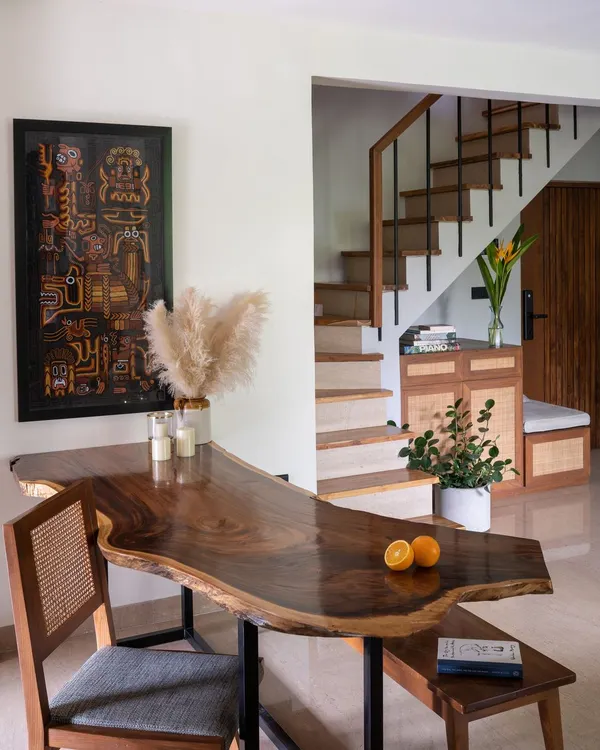The uniquely shaped live-edge wooden dining table is the heart of our penthouse, 301. Its organic form guides the flow between the living, dining, and staircase areas, tying the open-plan space together.