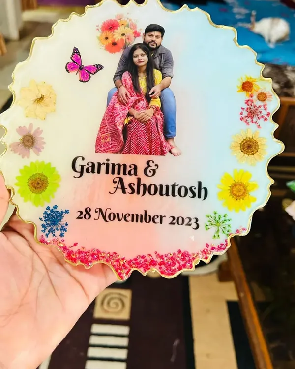 A close-up view of the personalized resin tabletop, showing the detail of the embedded flowers, butterfly graphic, and custom text. The zigzag edge adds a modern touch.
