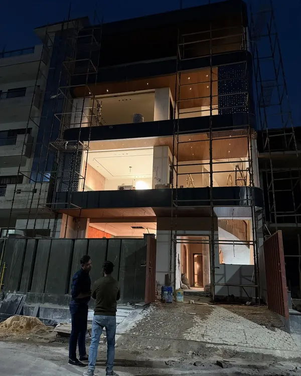 A night view of the independent house in Noida Sector 100. The multi-level lighting design highlights the wooden ceilings and open layout.
