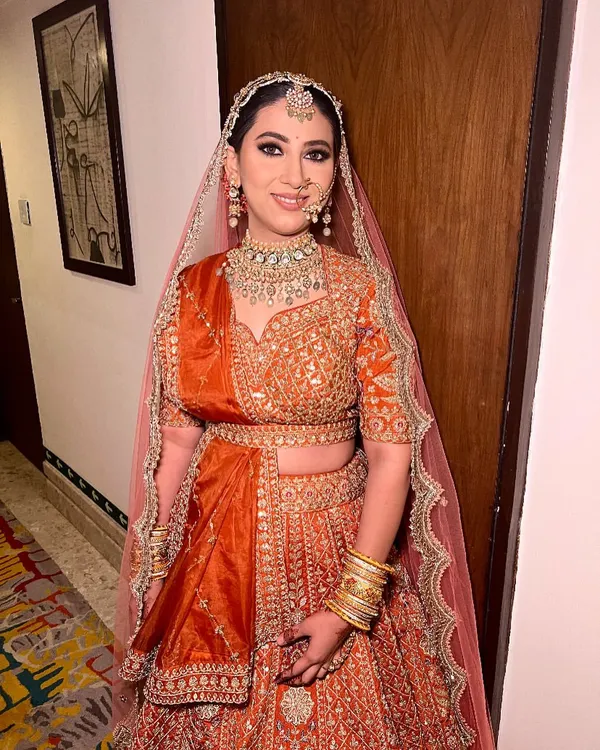 A full view of our magnificent orange bridal lehenga. The detailed embroidery across the entire skirt and the perfectly coordinated dupatta create a truly royal look for your wedding day.